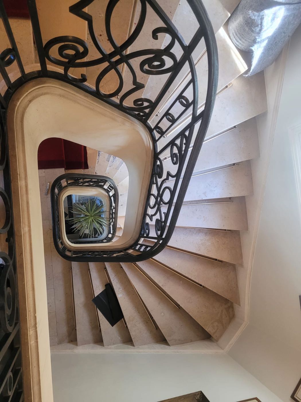 Escalier en marbre en colimaçon habillé d'un tapis avec tringles laiton